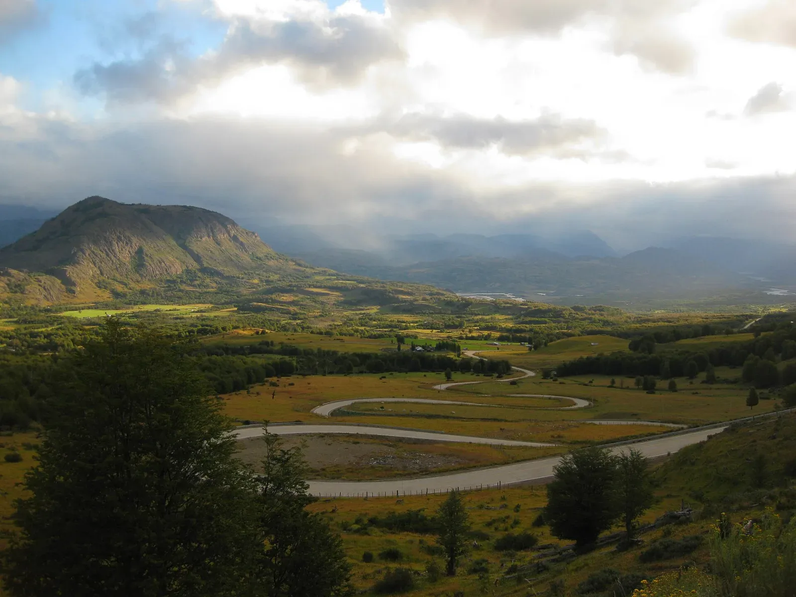 The Carretera Austral winding through a green Patagonian mountain valley